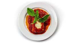 A plate with a slice of lasgna covered in marinara sauce